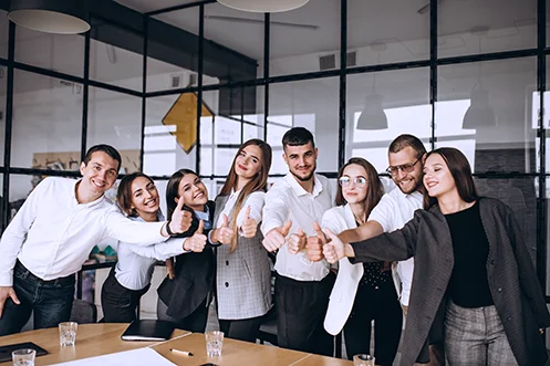 A group of people in an office giving a thumbs up